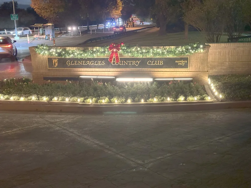 A club entrance decorated with lit garland and an oversized bow at night
