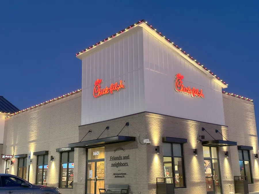 A commercial restaurant building outlined in warm white Christmas roofline lights at blue hour in North Texas