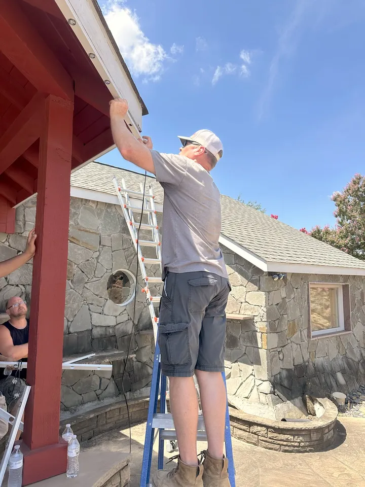 A South Custom Lighting crew on ladders installing holiday lighting at a covered pavilion