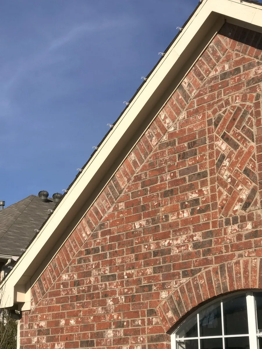 Christmas light clips seated cleanly along a brick gable with nothing nailed or stapled
