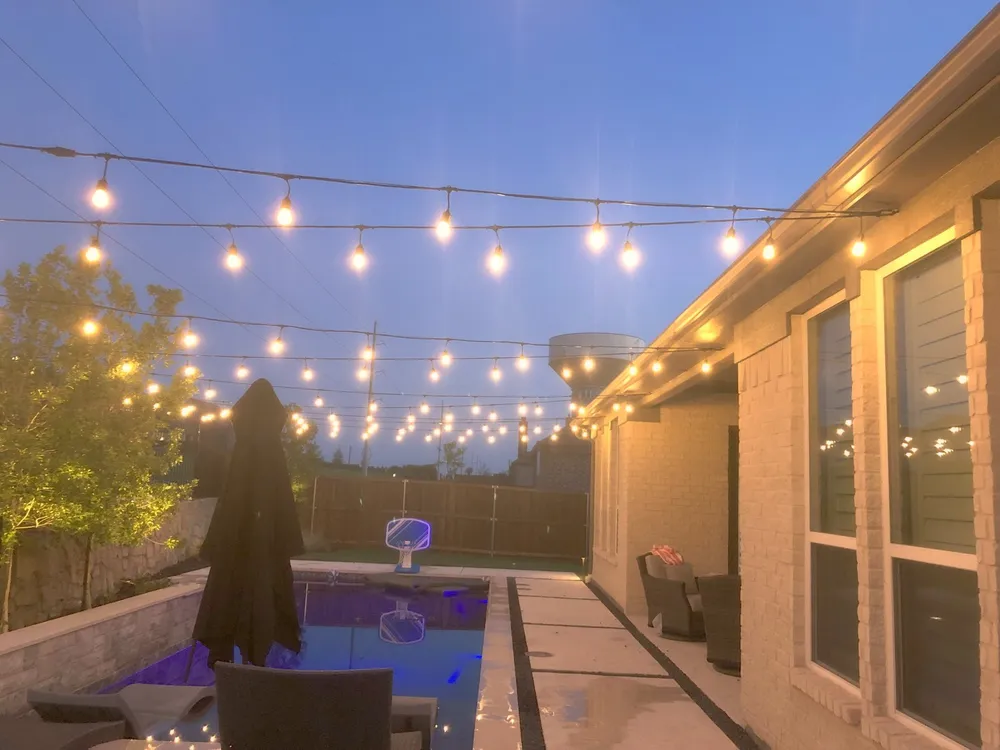 String lighting over a patio and pool at dusk