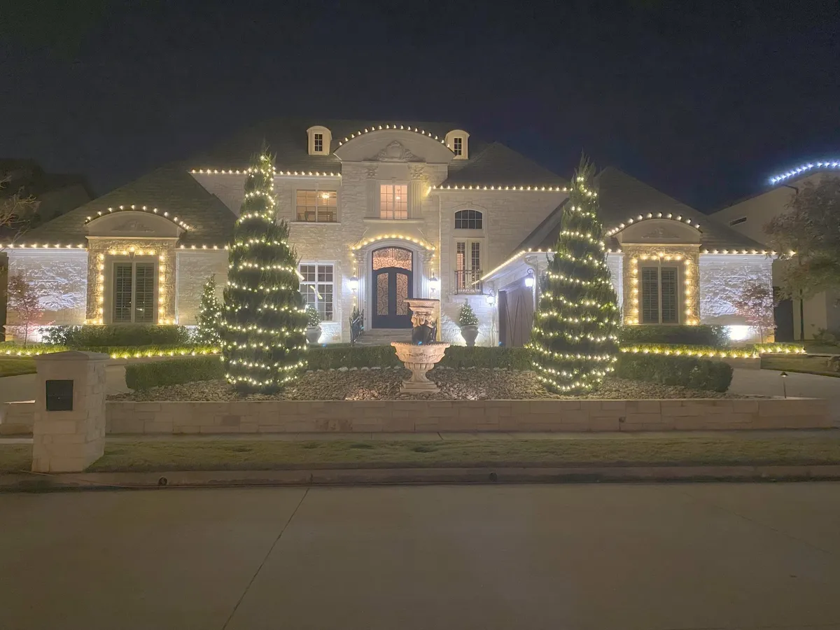 Warm white roofline with two evergreens wrapped trunk to tip, installed by South Custom Lighting in North Texas