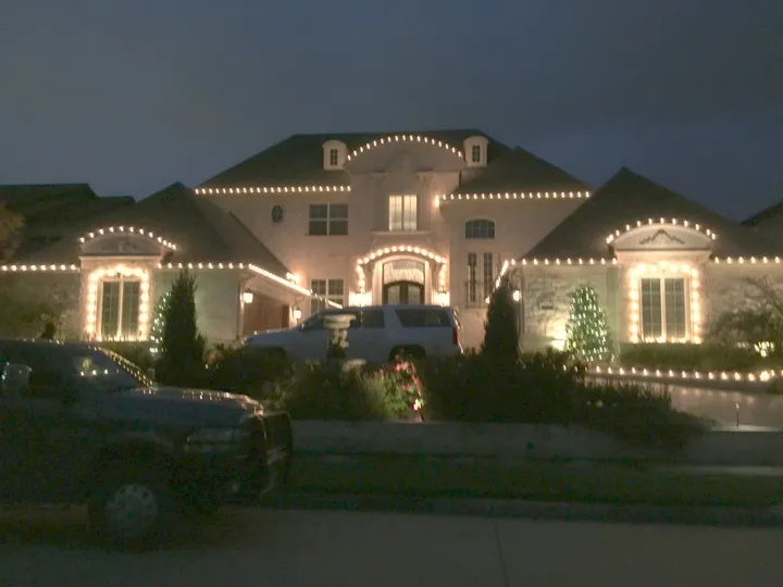 A North Texas stone home with every peak lit in warm white, staying that way all season