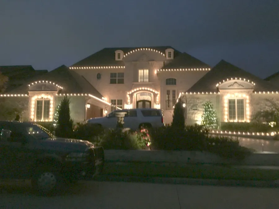 Warm white Christmas roofline lights on a North Texas home at night, the standard install South Custom Lighting runs in Denton