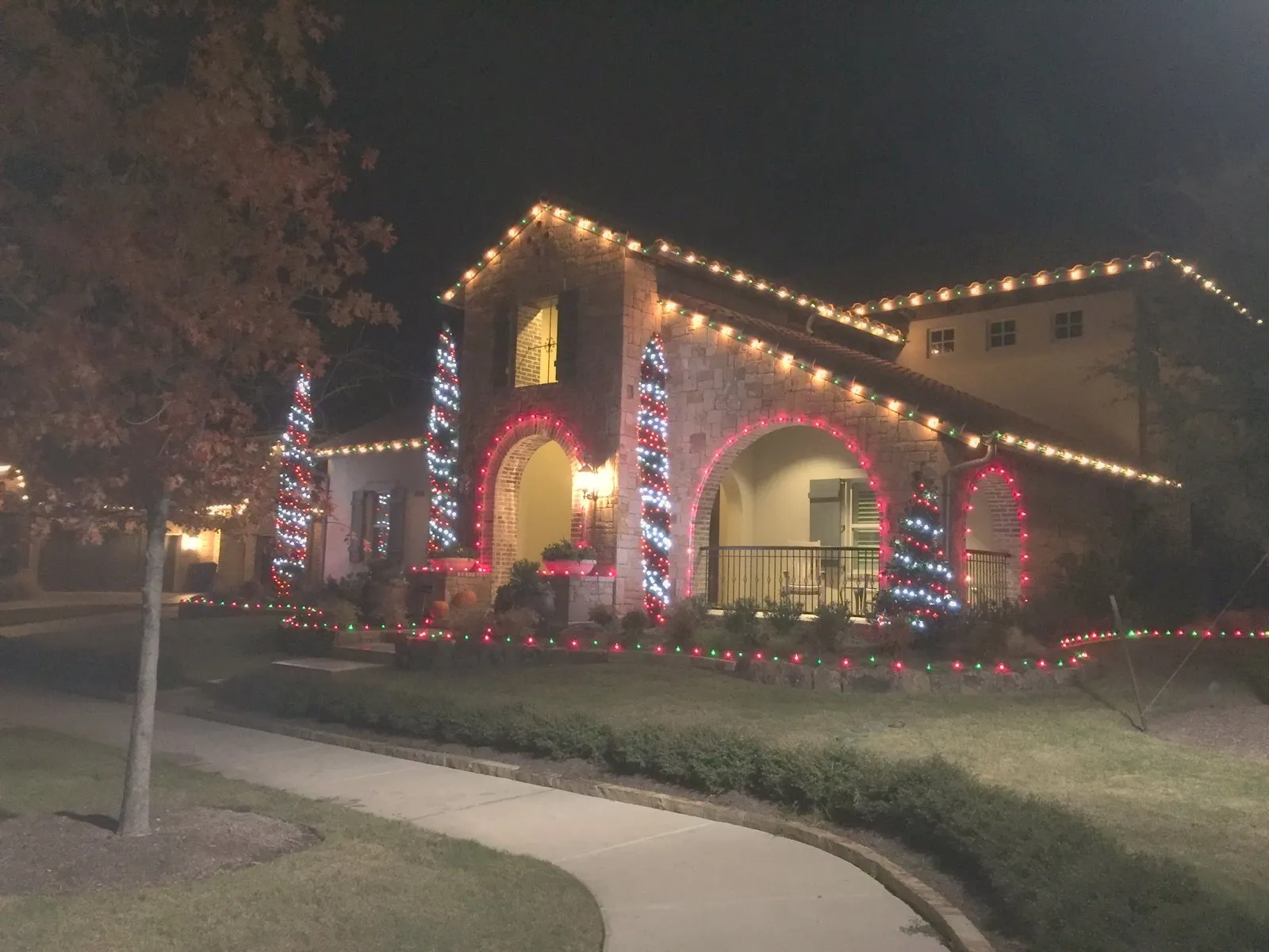 A North Texas home lit in colored architectural lighting along the roofline and arches at night