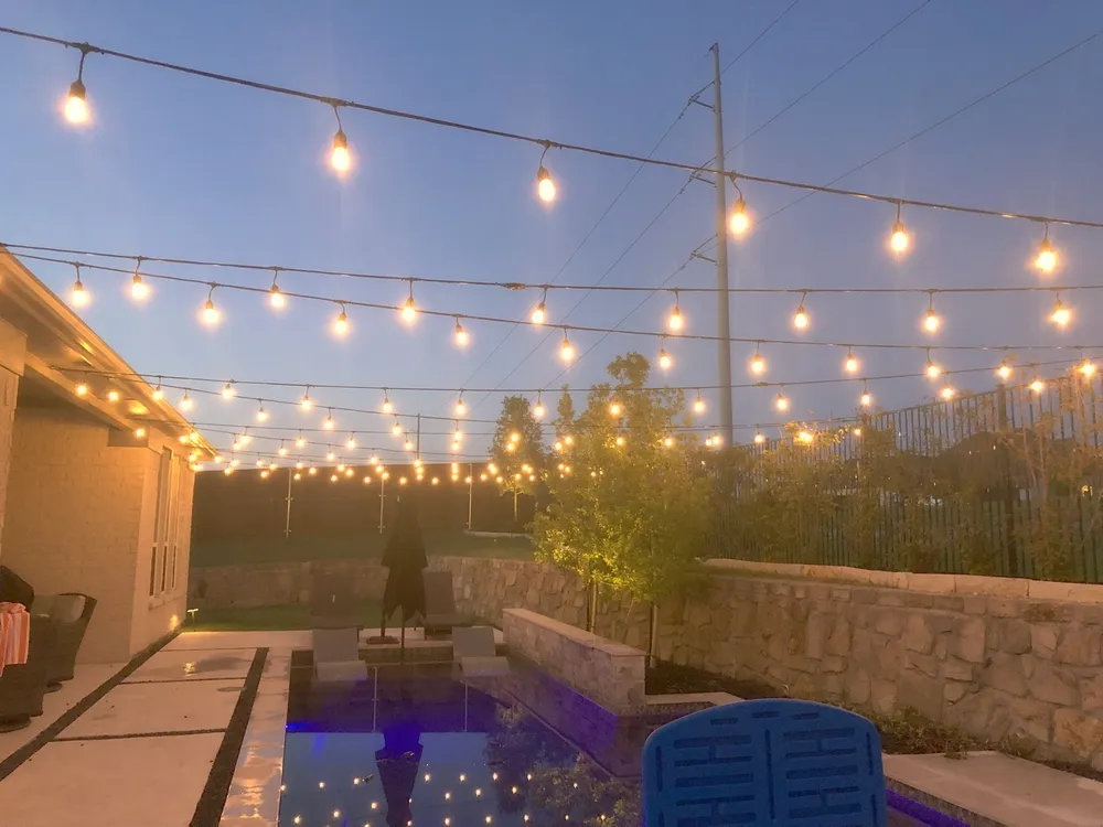 Bistro string lighting across a pool deck in the evening for an outdoor event